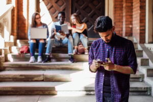 Portrait of handsome, african american student looking at cellphone